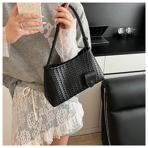 Detail of black woven leather tote bag with round buckle showing craftsmanship