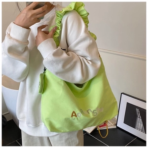 Détail du sac cabas vert vif avec bandoulière à volants et lettrage brodé