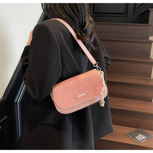 Détail du sac à bandoulière rose avec rabat tissé et breloque à pompon en corde stylée
