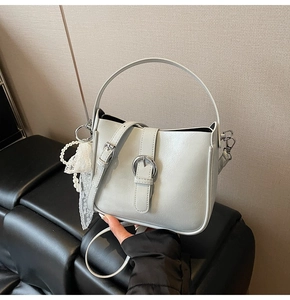 Detail of light grey leather bucket bag with top handle and pearl lace charm accessory