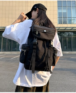 Rear view of a woman wearing a black technical nylon backpack in an outdoor urban setting