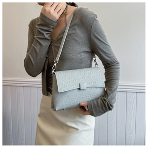 Detail of greyish-blue crossbody bag with geometric embossed pattern and pebble grain leather