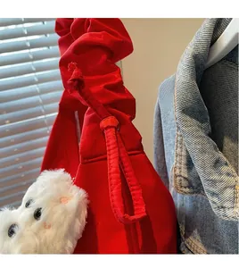 Close-up of red fabric shoulder bag with pleated strap and cute white bear charm