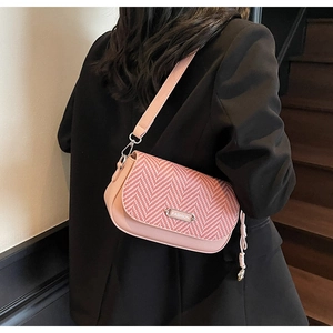 Détail du sac à rabat tissé rose avec plaque Fashion sur un blazer noir élégant