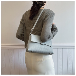 Detail of light blue embossed leather shoulder bag showing texture and metal feet