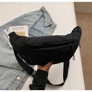Detail of a black nylon crossbody chest bag with adjustable strap and zip pockets