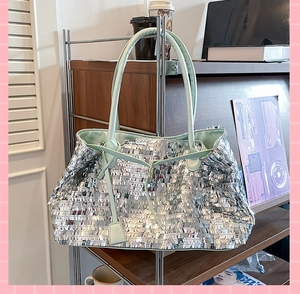 Detail showing shiny silver sequins and mint green leather handle on large tote bag