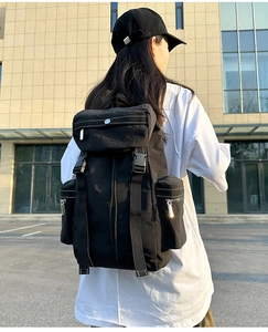 Outdoor back view of a black tactical multi-functional travel backpack with silver zippers