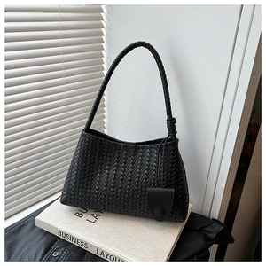 Detailed close-up of a black woven tote bag with knotted handle on books