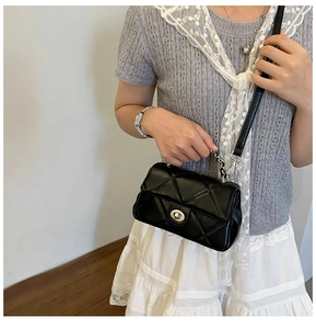 Close-up of black quilted chain bag featuring a silver metal turn-lock and leather strap