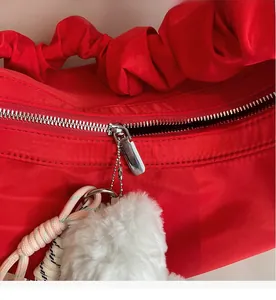 Detailed shot of a smooth metal zipper and red nylon texture on a large hobo bag