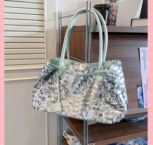 Close-up of silver sequin tote bag with mint green leather handles hanging on a stand