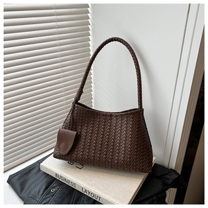 Macro detail of dark brown woven leather texture and matching decorative pouch charm