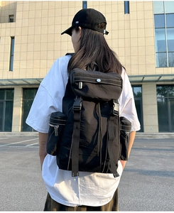 Detailed back view of a black multi-pocket travel backpack worn outdoors on a city street