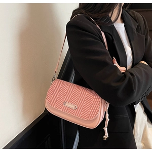 Vue détaillée du sac à bandoulière rose avec logo en métal et motif à chevrons tissé