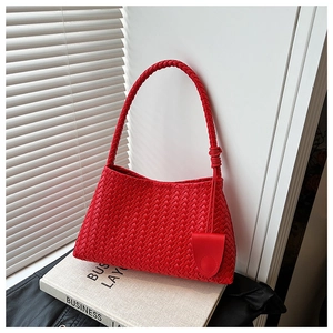 Detail of red woven leather tote bag with thick strap on a book and white background