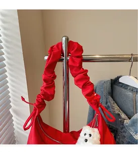 Detail of red shoulder bag with ruffled strap and a cute white puppy plush pendant
