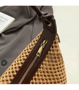 Vue détaillée du sac en paille tressée avec bordure en cuir marron et fermeture éclair dorée