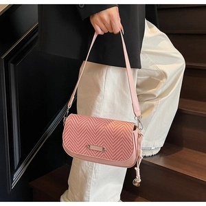 Détail du rabat tissé à chevrons rose sur le sac bandoulière avec plaque en métal dorée