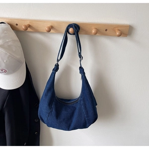 Detailed texture of dark blue denim crescent hobo bag with adjustable shoulder strap