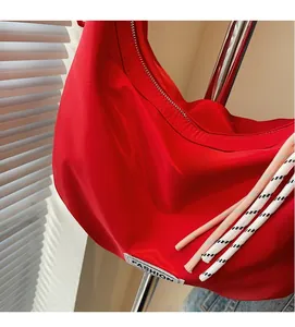 Detail of red nylon hobo bag showing pleated waterproof fabric and white fashion label
