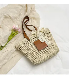 Detail of beige straw tote bag with brown leather handles and white lace bow decoration