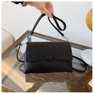 Detail of black embossed shoulder bag with geometric pattern and silver metal hardware