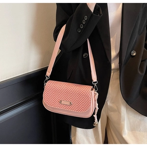 Détail du sac à rabat tissé rose avec plaque en métal fashion et bandoulière élégante