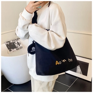 Détail du sac fourre-tout en toile noire avec imprimé lettres et petit porte-monnaie sur bandoulière