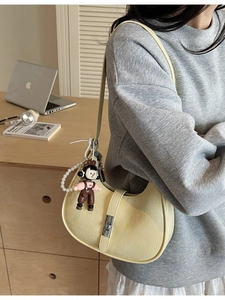 Minimalist light yellow lychee pattern hobo bag with a decorative pearl charm and doll