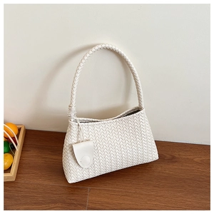 Close-up of cream woven shoulder bag with intricate texture and decorative charm