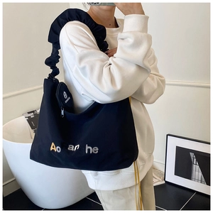 Détail du sac cabas noir en toile avec bandoulière plissée et petit porte-monnaie rond