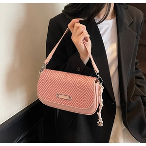 Détail du sac rose avec rabat en tweed rouge et pendentif en forme de cœur argenté