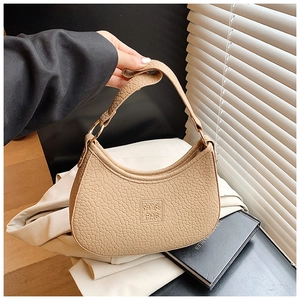 Detail of beige crescent shoulder bag with pebbled leather and gold hardware rings