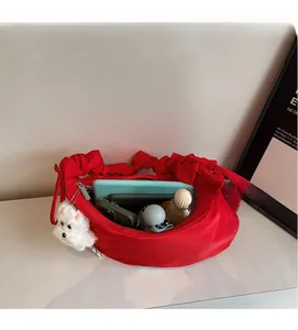 Top view of red nylon crescent bag showing large capacity with daily items and plush charm