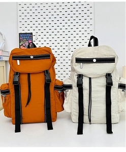 Detail of orange and off-white tactical backpacks with flap buckles and drawstrings