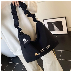 Vue détaillée du sac cabas en toile noire avec bandoulière plissée et pochette logo ronde