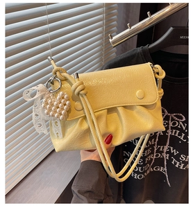 Détail du sac plissé jaune clair avec breloque cœur perle et nœud en dentelle