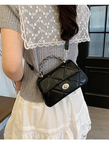 Elegant black quilted crossbody bag with silver chain strap shown on a model
