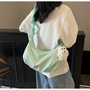 Detail of light green ruched nylon cloud bag with plush puppy charm and fashion label