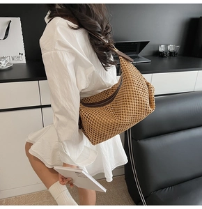 Détail du sac hobo en paille tressée avec bandoulière en cuir brun et texture maille