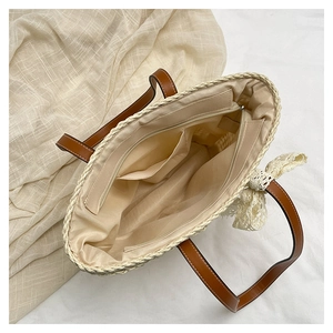 Top view of woven straw tote showing interior lining, zipper pocket, and leather handles