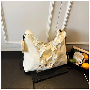 Détail des volants plissés sur le sac fourre-tout beige avec un petit porte-monnaie
