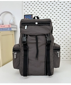Detail of grey travel backpack featuring buckle closure and side pockets in study scene
