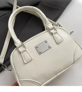 Detail einer cremeweißen Bowlingtasche mit feiner Textur und silbernen Metallbeschlägen
