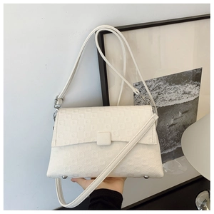 Close-up of the white square-quilted fabric texture and silver hardware on a shoulder bag