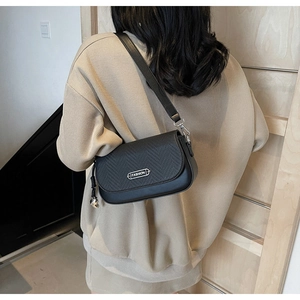 Gros plan du sac bandoulière noir avec texture tressée et pendentif en métal