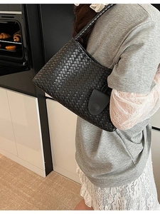 Black woven leather tote bag with matching pouch in a modern minimalist kitchen setting