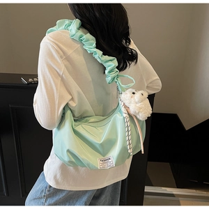 Detail of mint green nylon pleated shoulder bag with cute plush animal charm accessory