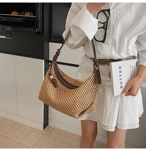 Détail du tissage de ce sac hobo en paille avec bandoulière en cuir marron et breloque